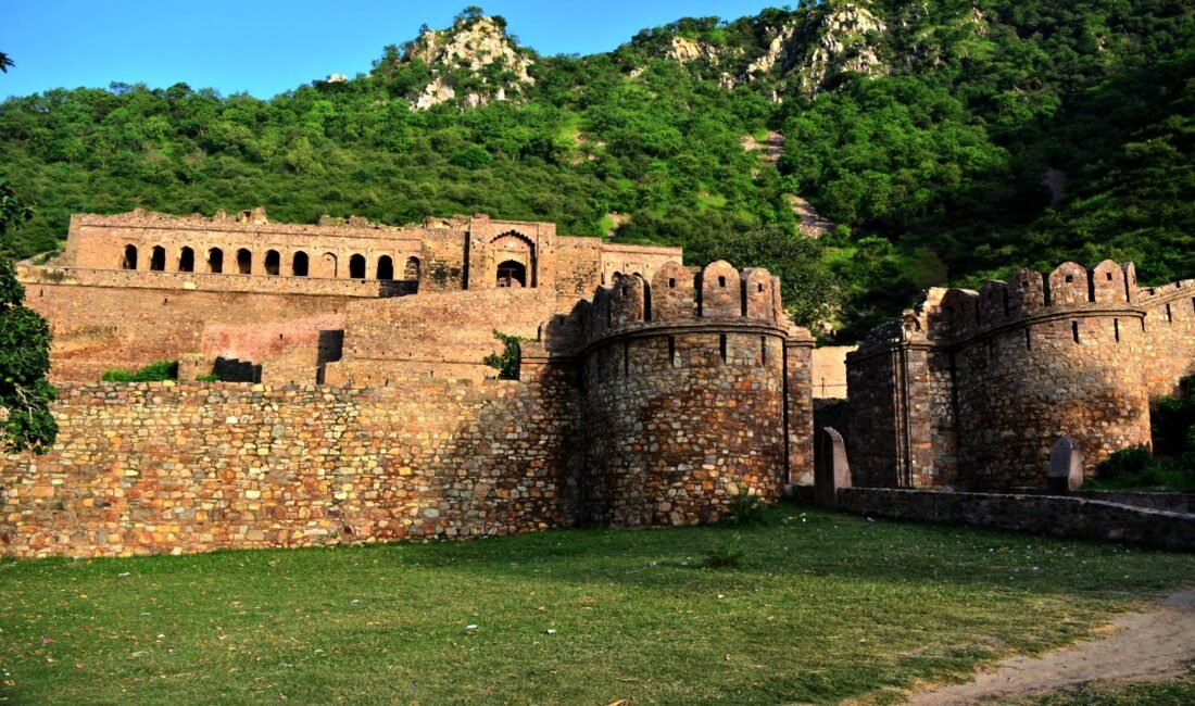 Wide landscape view of Bhangarh Fort walls against green Aravalli hills