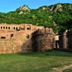 Wide landscape view of Bhangarh Fort walls against green Aravalli hills