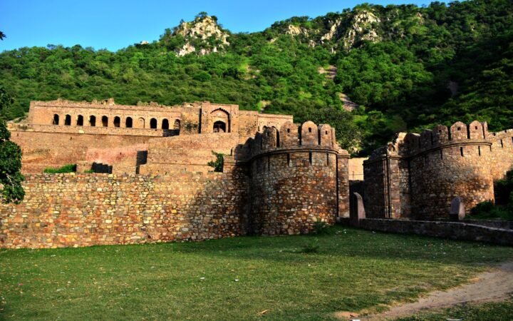 Wide landscape view of Bhangarh Fort walls against green Aravalli hills