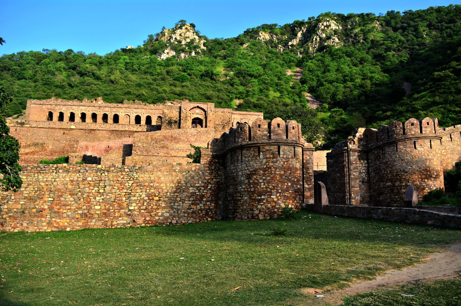 Wide landscape view of Bhangarh Fort walls against green Aravalli hills