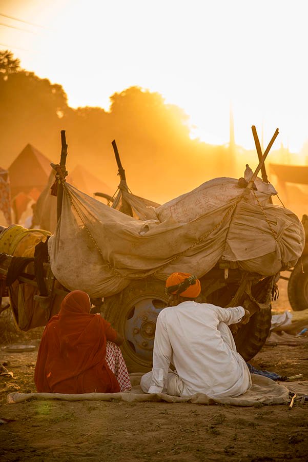 Camel traders sitting beside a cart at sunrise during Pushkar Mela